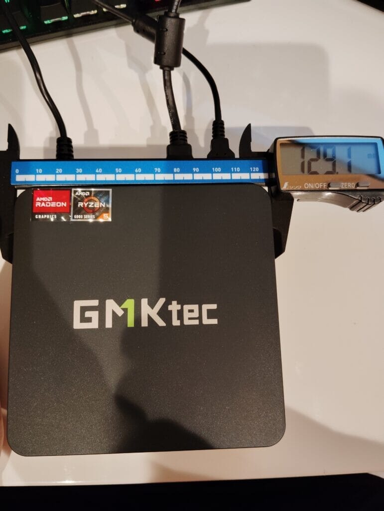 GMKtec製の黒い小型パソコンをノギスで測っている様子