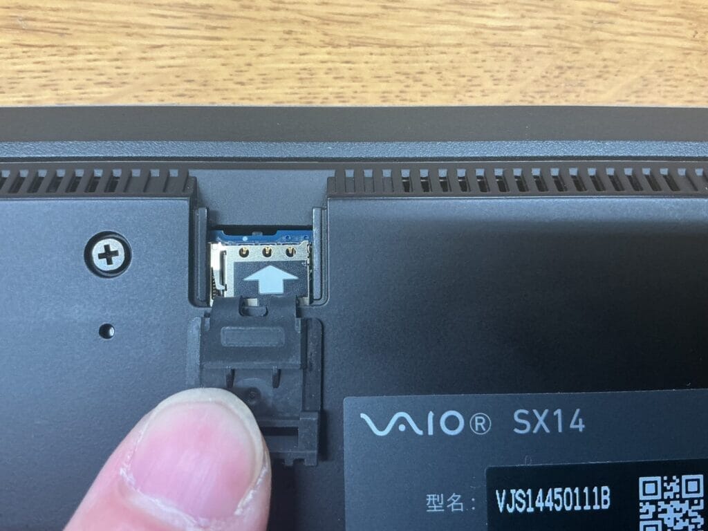VAIO SX14のSIMカードスロットに指でトレイを挿入する様子